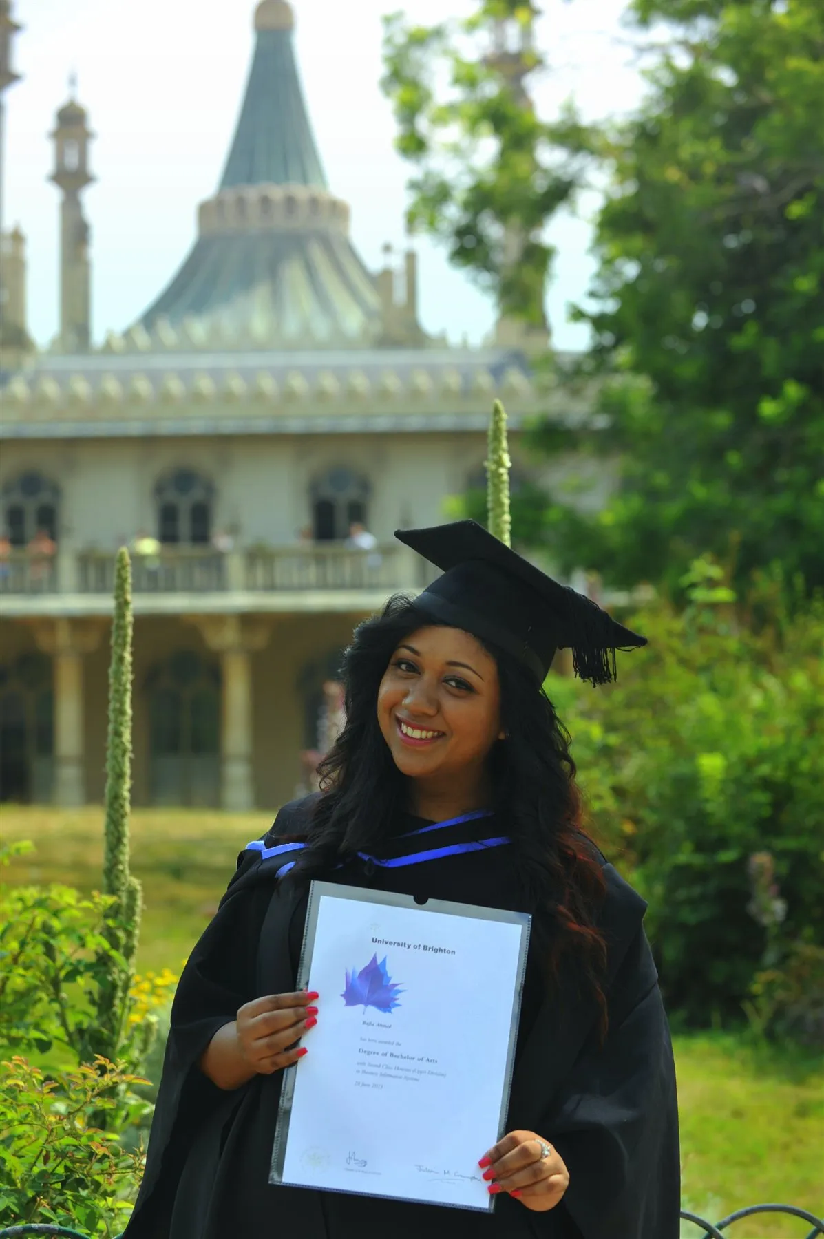 Graduate holding her certificate outside the university