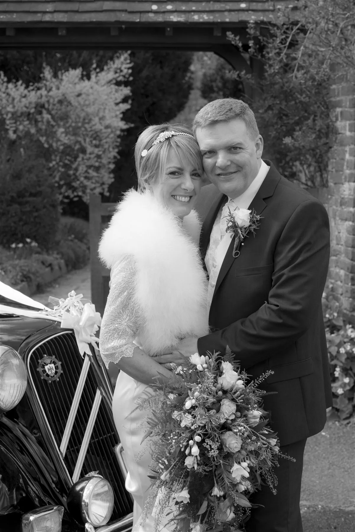 Bride and groom beside a classic wedding car