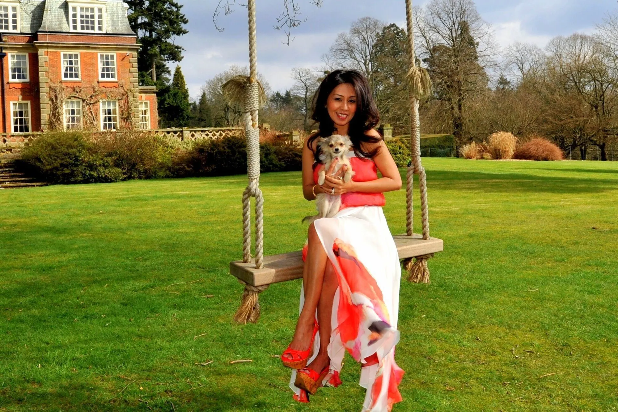 A woman in a coral dress posing in a garden